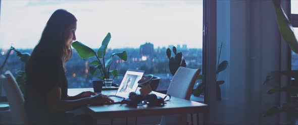 Woman photographer reviewing pictures in her office, wide shot