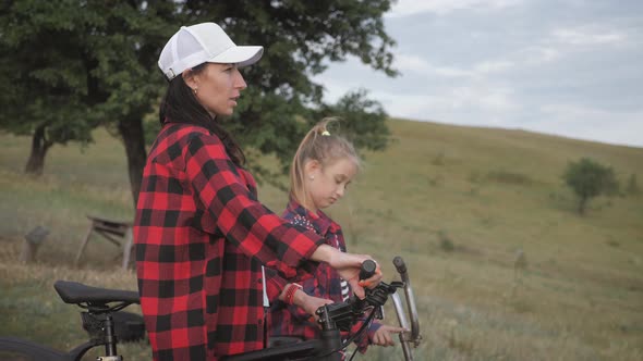 Young Mother and Daughter with Bikes on Mountain.