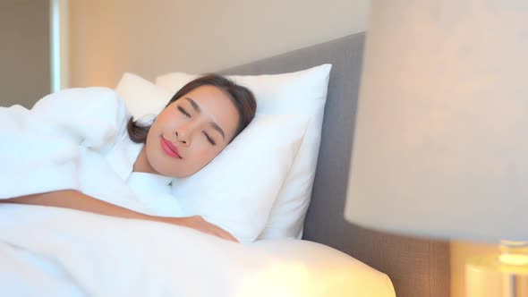 Asian woman relax on bed in bedroom interior