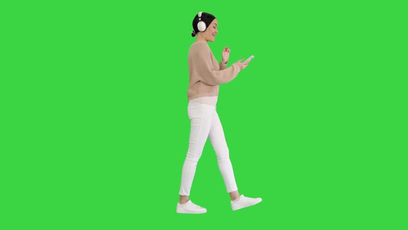 Happy Girl Walking Listening To Music with Smart Phone Wearing Headphones on a Green Screen, Chroma