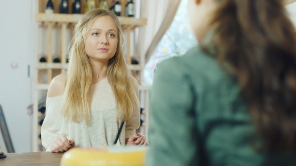 An Attractive Woman Buys Food in a Small Store, the View From the Side of the Counter