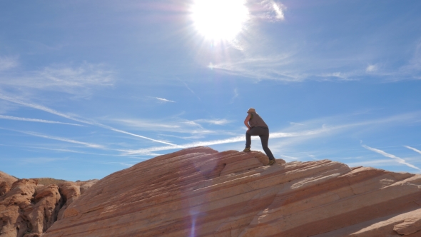 Sports Hiking Woman Climbs up the Red Rock Background the Sky