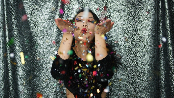 Young Brunette Woman Blowing on Confetti