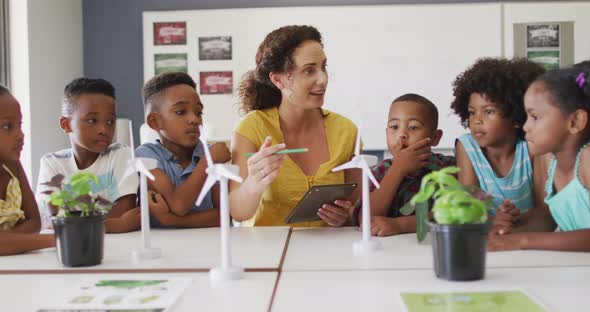 Video of happy caucasian female teacher and class of diverse pupils studying ecology in classroom