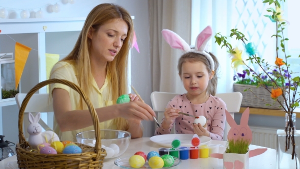 Mother and Her Little Daughter Coloring Easter Eggs
