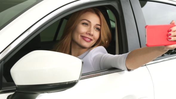 Happy Young Beautiful Woman Taking Selfies Sitting in Her New Car