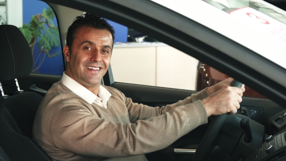 A Careful Man Is Studying the Steering Wheel of the Car and the Buttons Inside the Salon