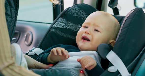 Camera Inside the Car Closeup Baby Car Seat Baby Boy Appears Carried on Hands of His Mother Who Puts