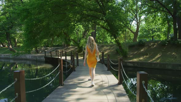 Woman walking on a bridge over a pond