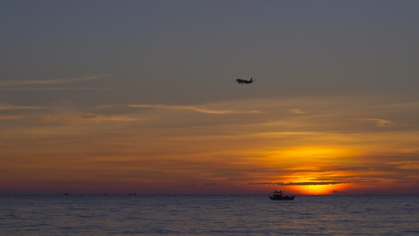Sunset on a Tropical Beach - View on a Sea with a Silhouette of an Airplane Landing