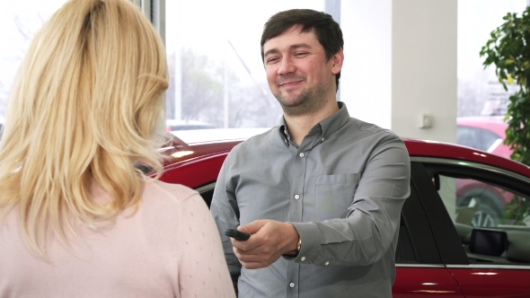 Happy Mature Man Handing Car Keys To a New Auto To His Loving Wife