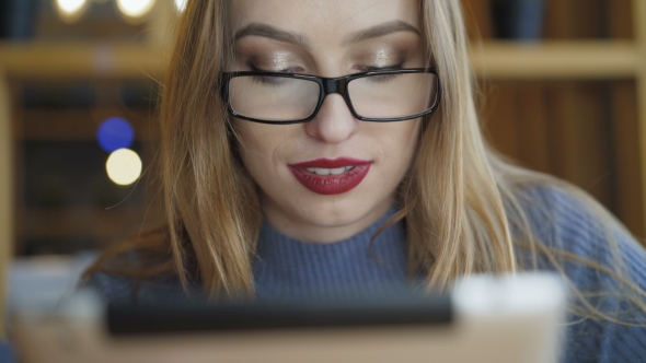 of Pretty Girl in Glasses Using Tablet in Cafe