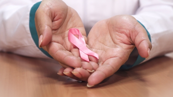 Female Doctor Holding Pink Ribbon for Breast Cancer Awareness