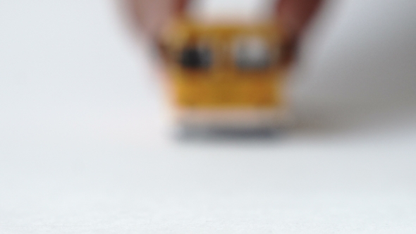 Male Hand Moving a Toy Bus Towards the Camera