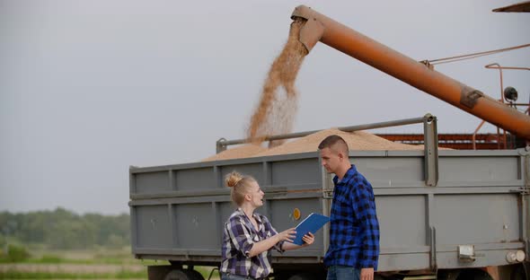 Agriculture - Female and Male Farmers Talking at Wheat Field During Harvesting