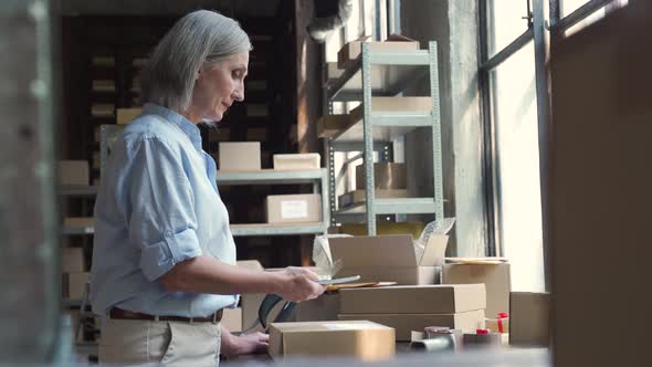 Female Small Business Owner Using Mobile App on Smartphone Checking Parcel Box