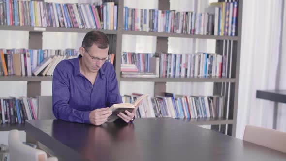 Serious Business Man Reading Book In A Library