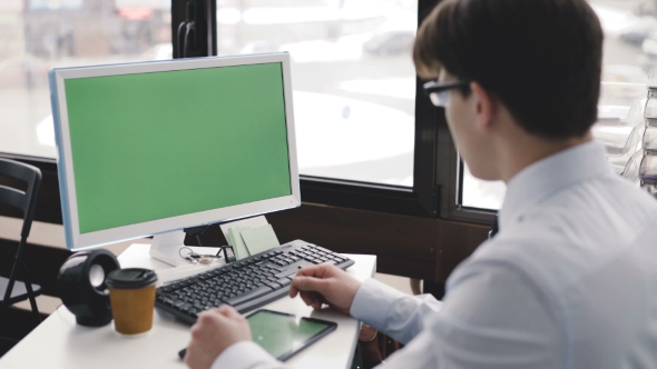 Young Man Works with Pc and Tablet with Green Screen