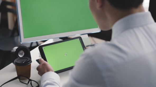 Young Man Works with Pc and Tablet with Green Screen
