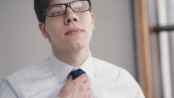 of a Man Straightens His Tie Near the Window