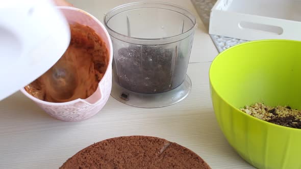 A Woman Makes Cream For A Chocolate Cake With Peanuts And Strawberries.