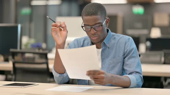 Young African American Man Celebrating While Reading Documents