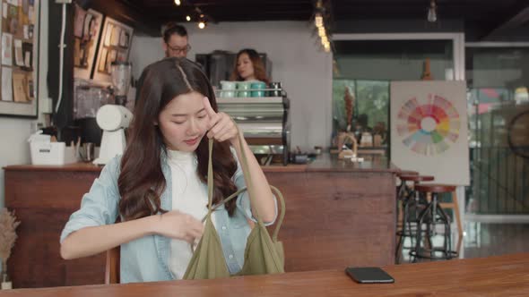 Cheerful Young Asian freelance lady working on laptop at coffee shop.