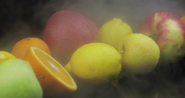 Tropical Lemon, Orange, Apple in Cold Ice Clouds of Fog Smoke on Dark Background