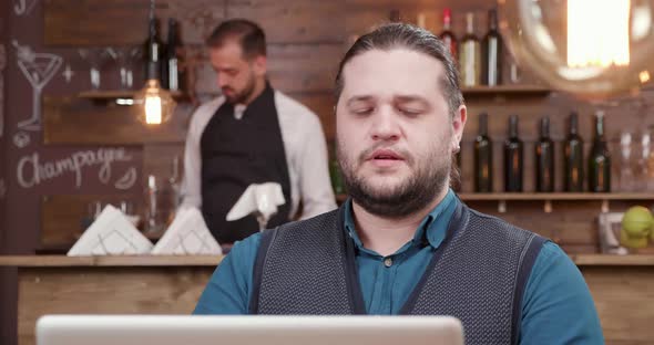 Man with Long Hair and Beard Having a Video Conference During a Coffee Break