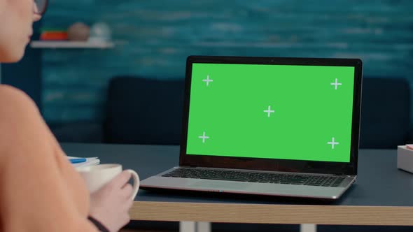 Young Adult Analyzing Laptop Display with Green Screen