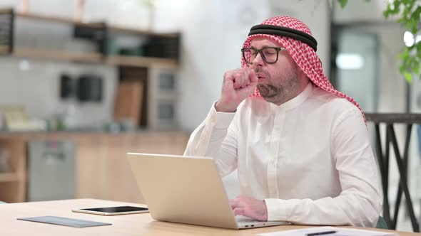 Sick Young Arab Businessman with Laptop Coughing in Office