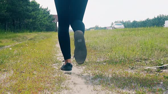 CU, Slow Motion, Low-angle Shot: Young Girl Goes in for Sports in the Morning, Runs Along a Pine