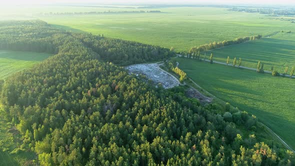 Aerial View Huge Rubbish Dump in Summer at Sunset or Sunrise Around the Forest