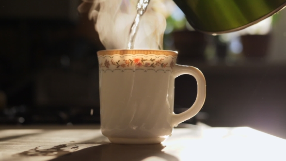 Kettle Pouring Boiling Water Into a Cup.