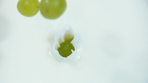 Berries of Green Grapes Are Dropped Into Fresh White Milk