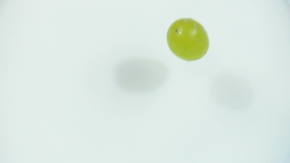 Berries of Green Grapes Are Dropped Into Fresh White Milk in