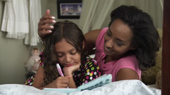 Slow motion pan of mother and daughter writing in book.