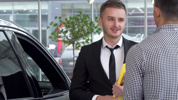 Car Dealer Shaking Hands with Male Customer After Selling an Automobile