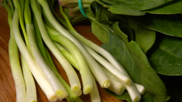 Spinach, fennel, parsley and green onions leaves on a wooden cutting board.