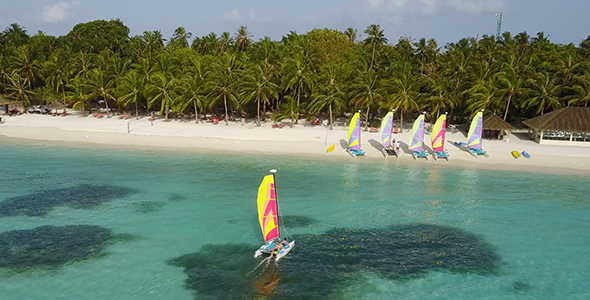 Aerial Shot of Couple Sailing on a Colourful Catamaran Towards Tropical Island