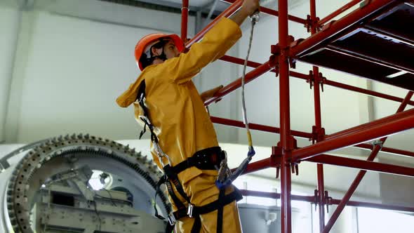 Male worker moving down from scaffolding at solar station