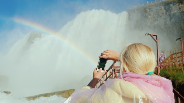 Tourism in the US - a Woman in a Raincoat Takes Pictures of the Famous Niagara Falls in a Cave of