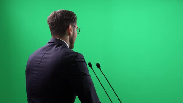 Back View of an Elegant Man Standing on a Green Background the Lecturer Speaks to the Audience and