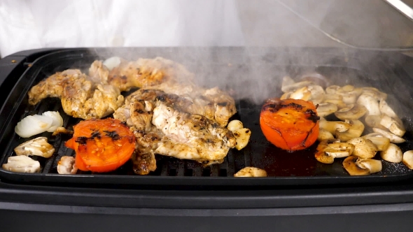 Taking the Lid of a Grill with Meat and Mushrooms