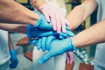  men in blue gloves and one woman in pink gloves. Themes health care, cooperation, trust and success.