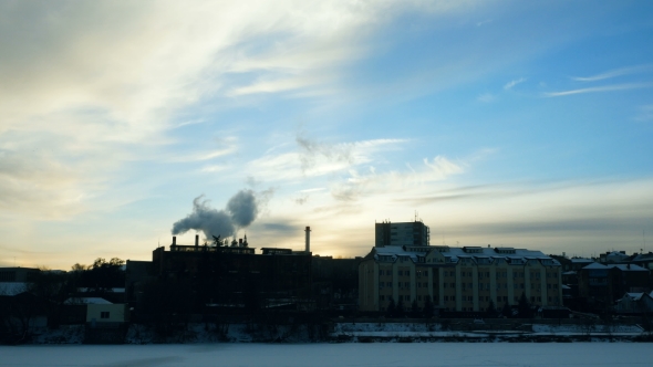 Winter City on the River. From the Chimney of the Plant Comes Thick Smoke