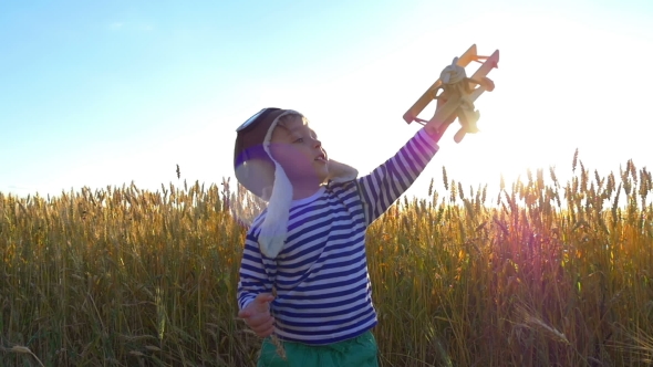 Happy Kid Playing with a Toy Airplane Against the Blue Sky