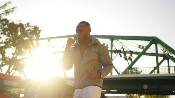 4K African man in sportswear do sport training boxing exercise in the city at summer sunset.