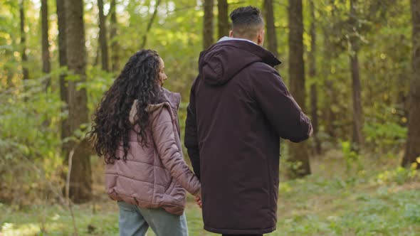 Back View Young Loving Carefree Joyful Hispanic Couple Walks in Autumn Park in Nature Enjoying