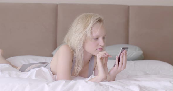 Woman lying on bed and using smart phone 